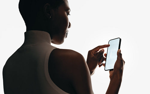 Silhouette of woman holding smartphone with blank screen for mockups