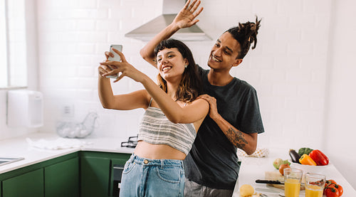 Cheerful young couple taking a selfie in the kitchen