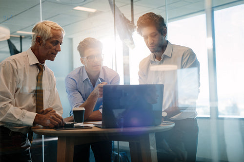 Colleagues looking at laptop and discussing during meeting
