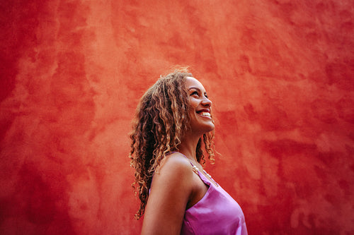 Smiling woman looks upward in a studio portrait against a red background