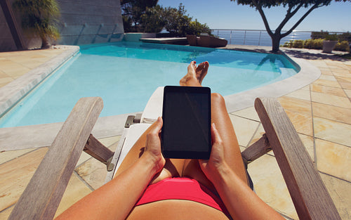 Young woman using a tablet PC near the pool