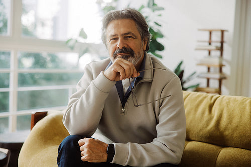 Senior man sits with glasses at home in retirement