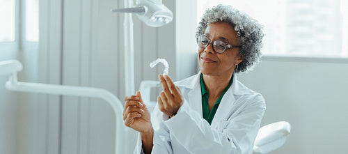 Female dentist in a modern clinic examines a dental aligner in her dental office