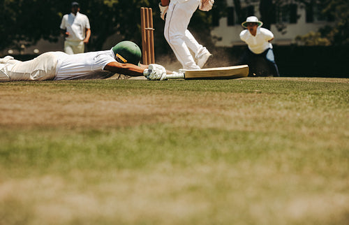 Cricket player diving to crease to avoid run out during intense match play