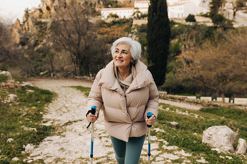 Active senior woman hiking with trekking poles outdoors