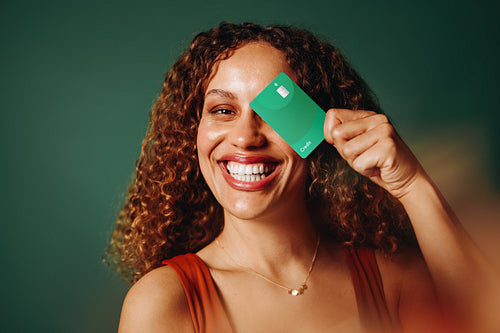 Woman holding banking card and smiling in studio portrait about personal finance