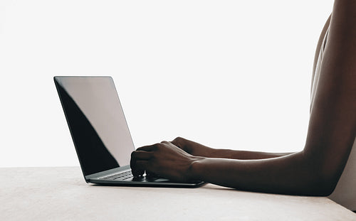 Person working on a laptop with a minimalist white background