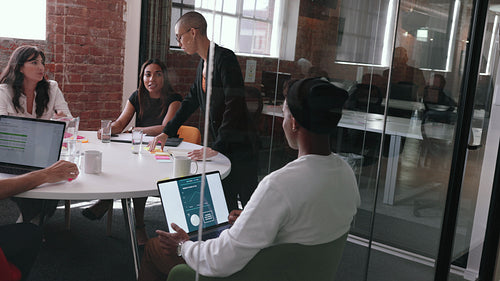 Confident female professional talking to her team in an office meeting, taking the lead on a project