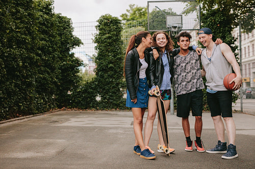 Teenage friends with skateboard and basketball