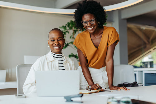 Happy businesswomen collaborating on a laptop in a modern office