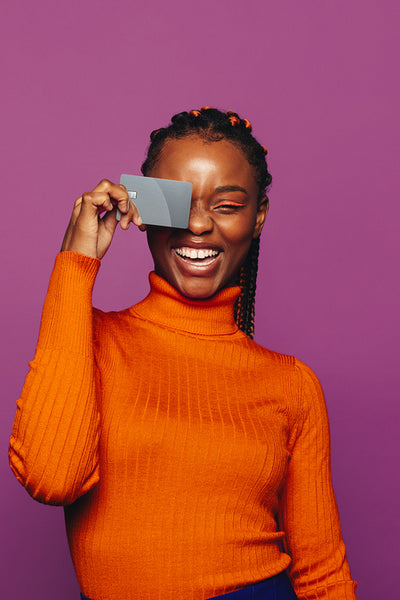 Cheerful woman paying with contactless card on a vibrant purple background