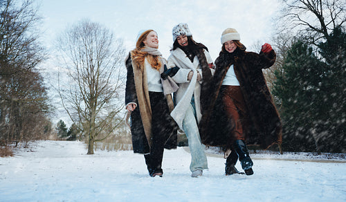 Women walk laughing together in a snowy winter park