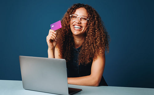 Woman shopping online with laptop and credit card at home office desk