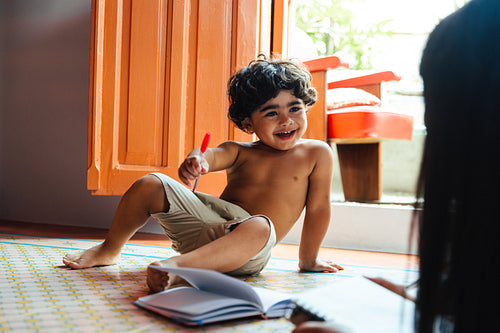 Happy child playing and learning with a marker in a bright home
