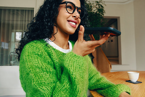 In a home office, a woman is speaking on a smartphone at her desk