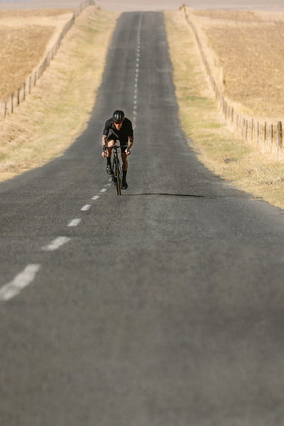 Cyclist riding bike on long asphalt road