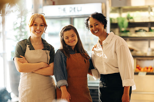 Happy retail workers smiling at the camera in a grocery store