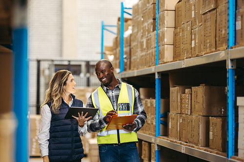 Cheerful warehouse managers smiling while recording inventory