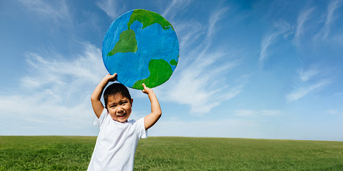 Child holds globe outdoors for environmental awareness