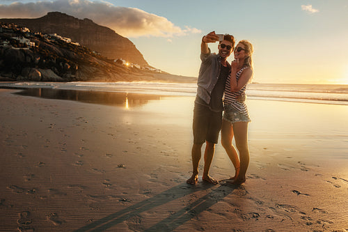 Romantic young couple taking selfie at the beach