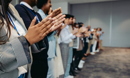 Colleagues applaud at business conference presentation in workplace setting