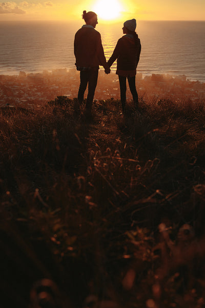 Loving couple on mountain peak during sunset