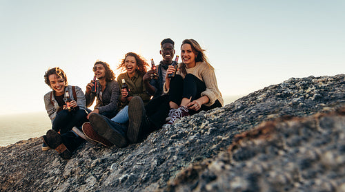 Diverse group of friends having beers on mountain top