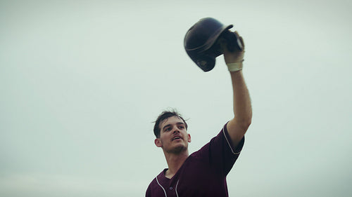 Baseball player celebrates victory with helmet salute.