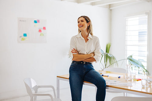Happy businesswoman sitting on a conference table in an office