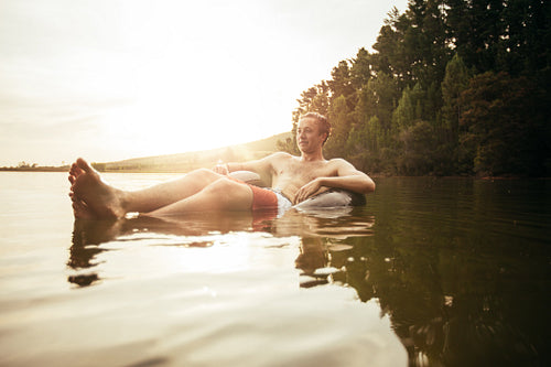 Young man in lake on inflatable ring