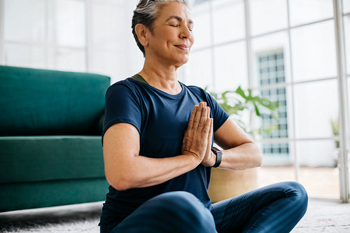 Prayer pose meditation for ageing wellness: Mature woman practicing yoga