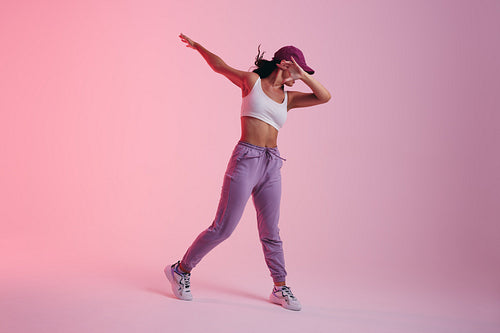 Young woman doing the dab dance move in a studio