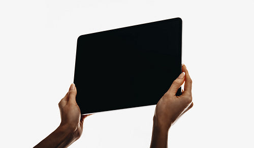 Hands holding a black blank digital tablet on a white background