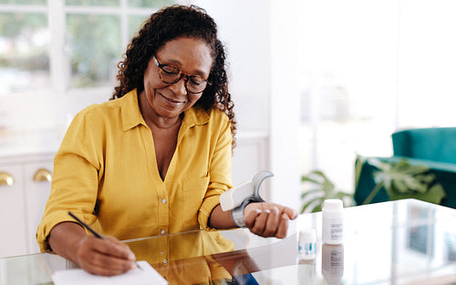 Mature woman monitoring her health with a home blood pressure monitor