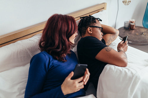 Couple in bed using mobile phones