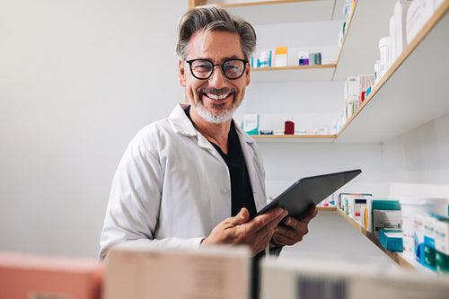 Happy pharmacist holding a tablet in a drug store