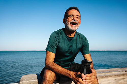 Mature man relaxing outdoors smiling by the ocean on a sunny day