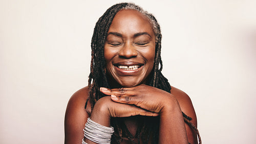 Cheerful woman with dreadlocks smiling with her eyes closed