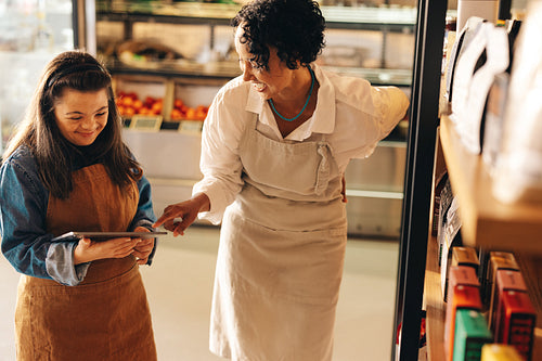 Cheerful grocery store owners using a digital tablet together