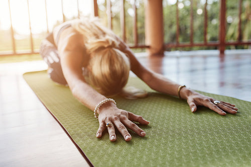 Fitness female performing balasana yoga at gym