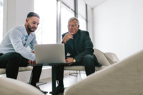 Two business people discussing working in office foyer
