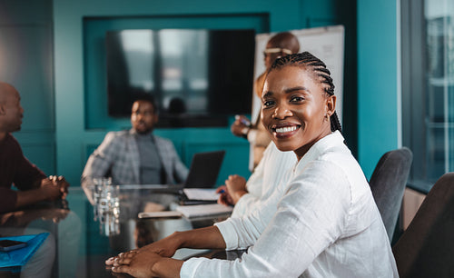 Happy business woman sitting in a corporate boardroom meeting with coworkers