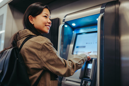 Young woman using transit ticket machine at station