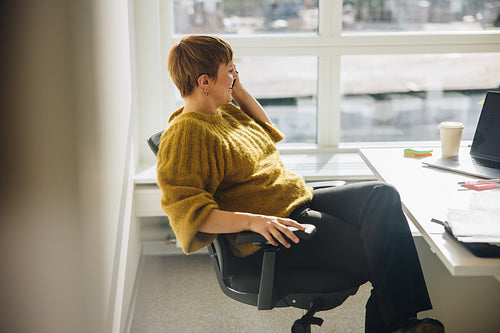 Female executive talking over phone sitting at her desk