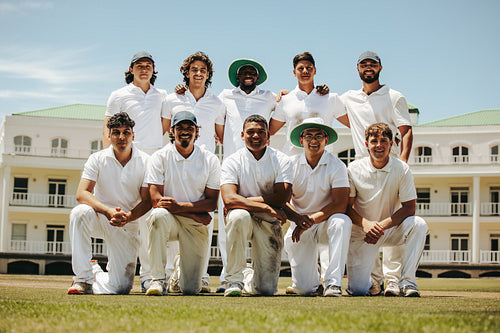 Team of cricket players posing on the field in white uniforms