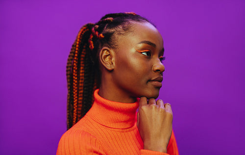 Stylish woman with colorful makeup, braids and purple background