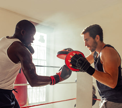 Boxer practicing uppercut punches with a personal trainer