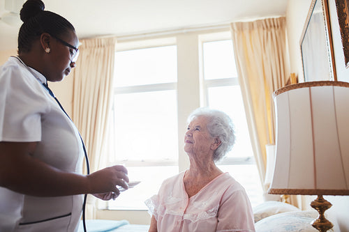 Female nurse assists an elderly female patient with medicines