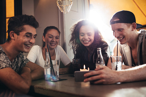 Group of friends in a cafe looking at mobile phone