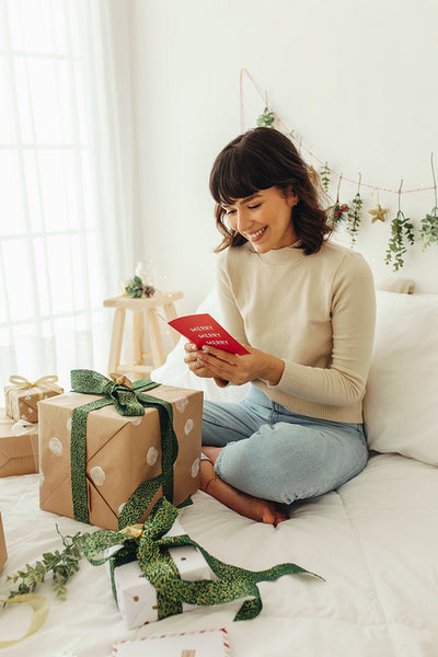 Woman reading a christmas greeting card sitting on bed